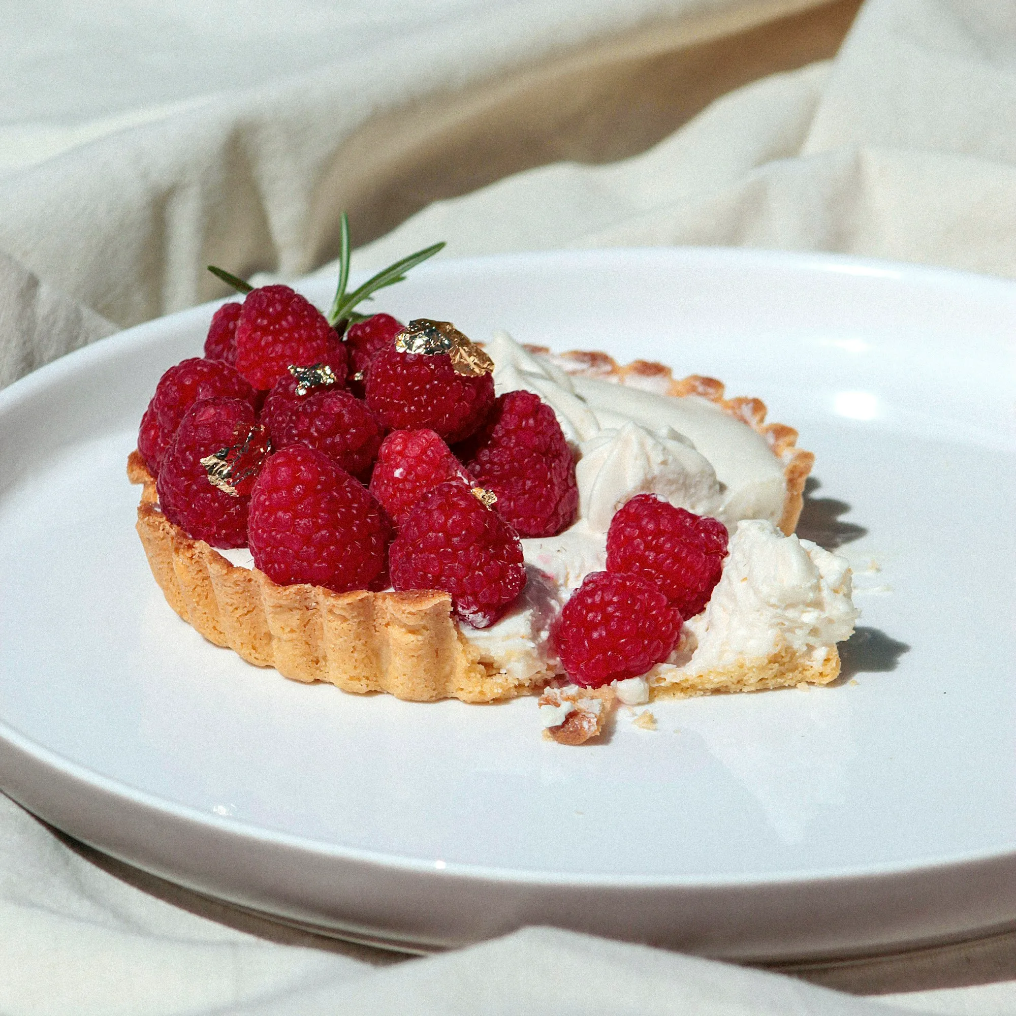 A raspberry tart with whipped mascarpone on a white plate